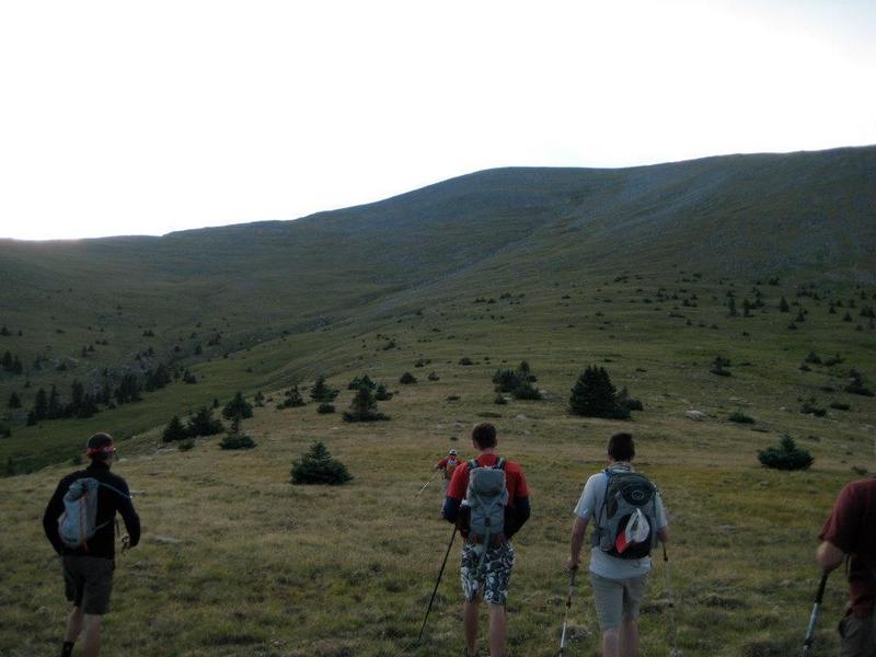 Hiking along the grassy slope toward the ridge. The drainage can be seen to the left.