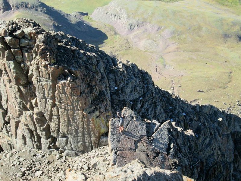 A hiker approaches the summit block. The technical formation behind him is not a part of this hike. There are many excellent scrambling options in this area. Have fun, but be careful!