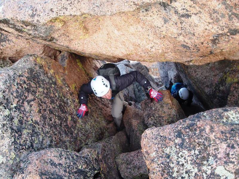 A hiker navigates the bizarre chimney just below Sunlight Peak's summit.