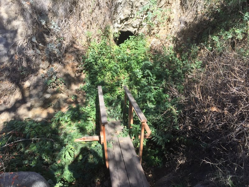 Sketchy bridge to a water filled cave