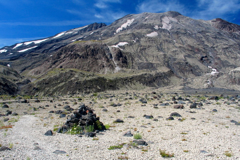 A rock cairn marks the route with Mt. St. Helens in the background.