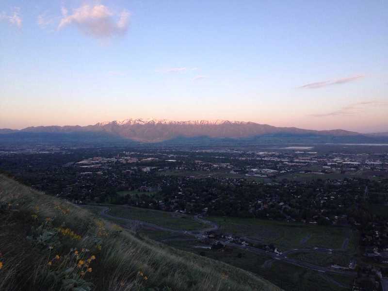 A view of the sunrise over the Wellsville mountains with the shadows of the Bear River Range just below them, and then Cache Valley in the forefront, all witnessed from the Saddleback Mountain Trail.