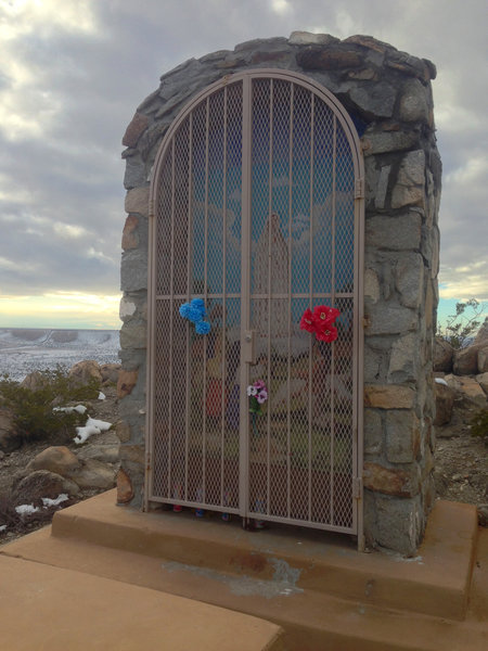 One of the trail's shrines, this one to the Virgin of Fatima. It is kept locked on non-event days. In the distance, the border fence can be seen crawling up the mesa, marking the international boundary.