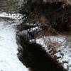 The creek with some fresh fallen snow on the side.