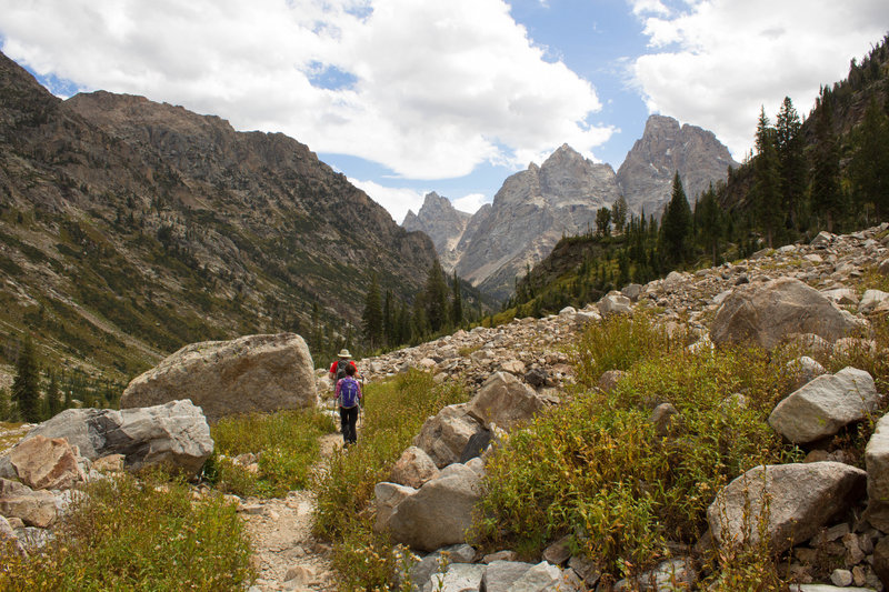 Hiker descending Upper Cascade Canyon with Grand Teton in the background.