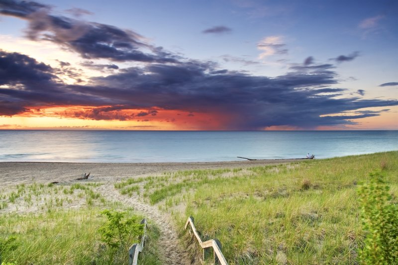 A solitary person sitting on the washed up tree. An amazing Lake Michigan sunset mixed with an impending thunderstorm. Incredible colors. Photo taken in between the Dunbar and Lakeview parking lots at Derby Ditch.