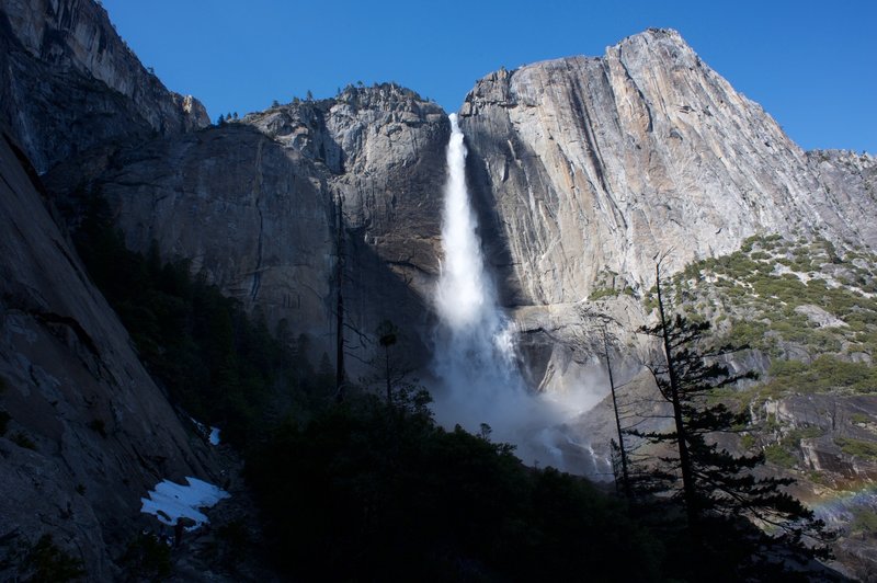 The trail hugs the rock wall on the left as Upper Yosemite Falls shines in the late noon sunlight.  When the spring snowmelt happens, the falls run at full force.