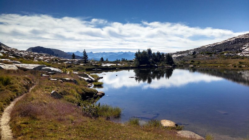 Small alpine lake along Isberg Trail with the Silver Divide and John Muir Wilderness high country in the distance.