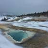 A winter trek around Geyser Hill is an excellent way to spend your time in the Old Faithful area. Here, beautiful Heart Spring's runoff channel heads to the Firehole River (with the geyser cones of the Lion Group behind).