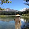 A woman enjoys a snack along the southern portion of the Manzanita Lake Loop Trail. Chaos Crags (right) and Lassen Peak (left) rise above.