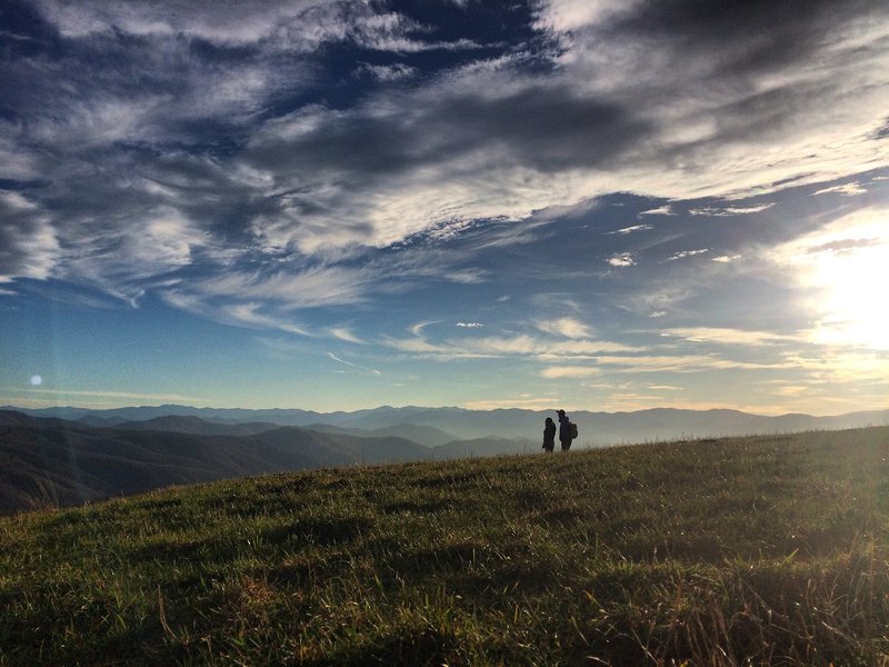 The Peoples Trail - A photo shot of a couple along the Appalachian Trail from atop Max Patch Mountain in Pisgah National Forest. There are many stunning views along the 2,200-mile east coast trail, but nothing quite like the panoramic scene of the Blue Ridge Mountains.