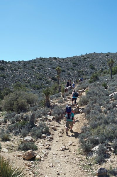 Hikers pass through the saddle and continue the ascent to the summit of the mountain.