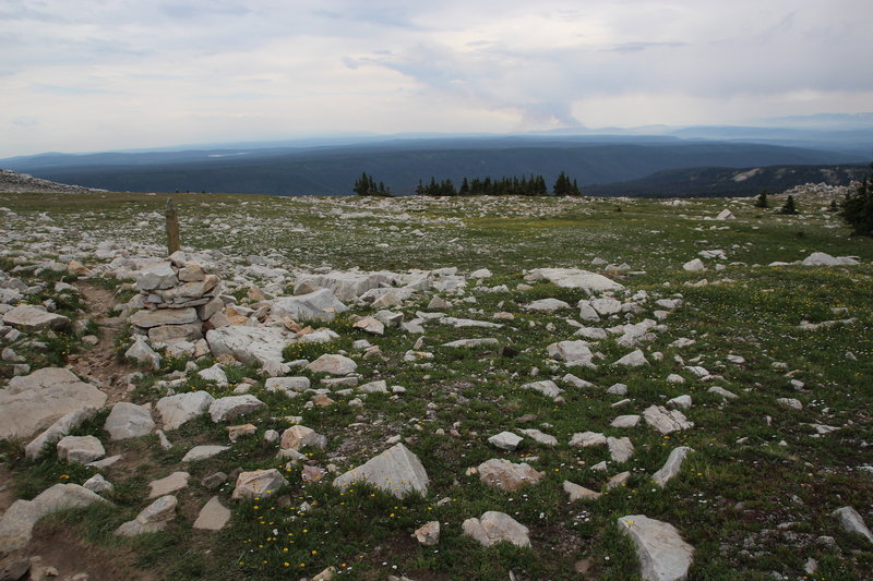 Rock piles with wooden posts mark the trail. The Beaver Creek Fire can be seen in the distance burning in northern Colorado.