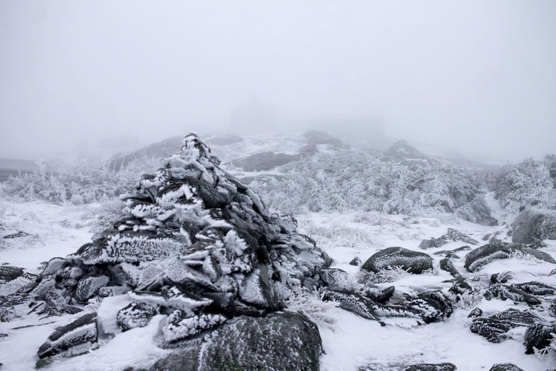 With 50 ft visibility, you can just barely make out the outline of Lakes of the Clouds hut in the background behind the cairn.