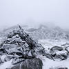 With 50 ft visibility, you can just barely make out the outline of Lakes of the Clouds hut in the background behind the cairn.