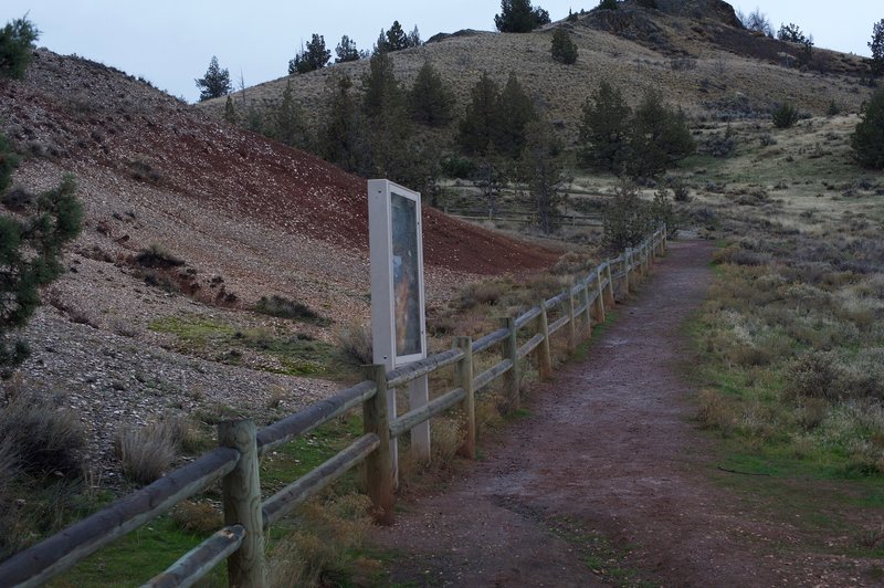 The fence separates visitors from the fossil hill. The sign talks about the history of the hill and has examples of some of the fossils found here.