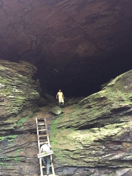 A hiker climbs the ladder into Honey Creek Rock House.