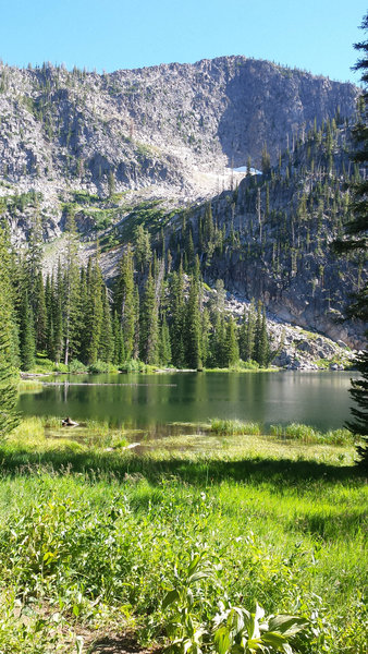 A glassy Snowslide Lake glints in the midday sun at the foot of Snowslide Peak.