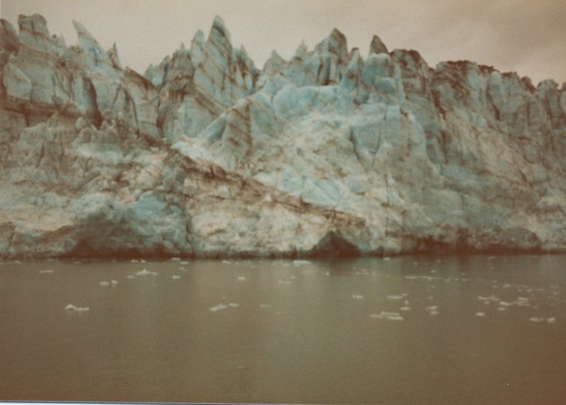 Marjerie Glacier poses with tiny remnants of calved icebergs floating in front of it.