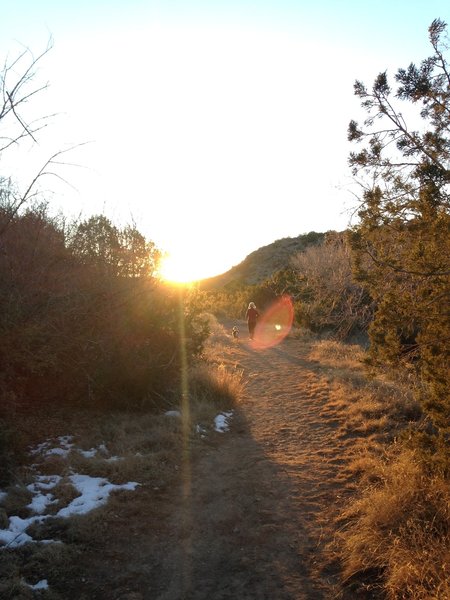 A woman and her dog head west from Bridal Veil Falls chasing the sunset.