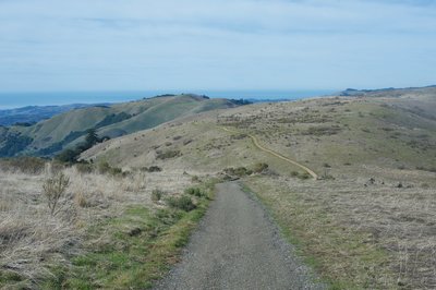 The trail turns to gravel toward the end. The Ridge Trail can be seen climbing the hillside in the distance.