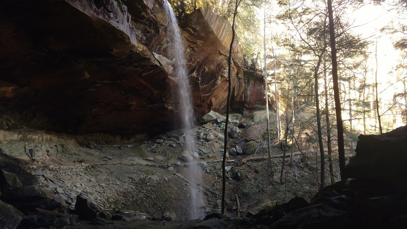 Yahoo Falls cascades over the trail tucked into the shelter of the cave.