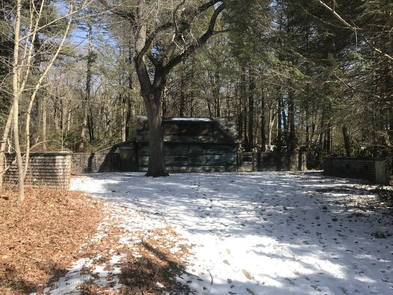 A carriage house stands shaded in the woodlands of Maudslay State Park.