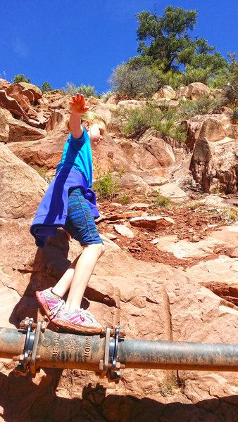 A child tries her hand at traversing a pipe along the Kanarra Creek Trail.