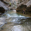 A hiker edges through the narrows of Lower Death Hollow.