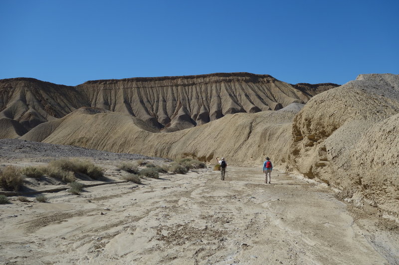 Two hikers make their way through a wash toward the Elephant Knees.