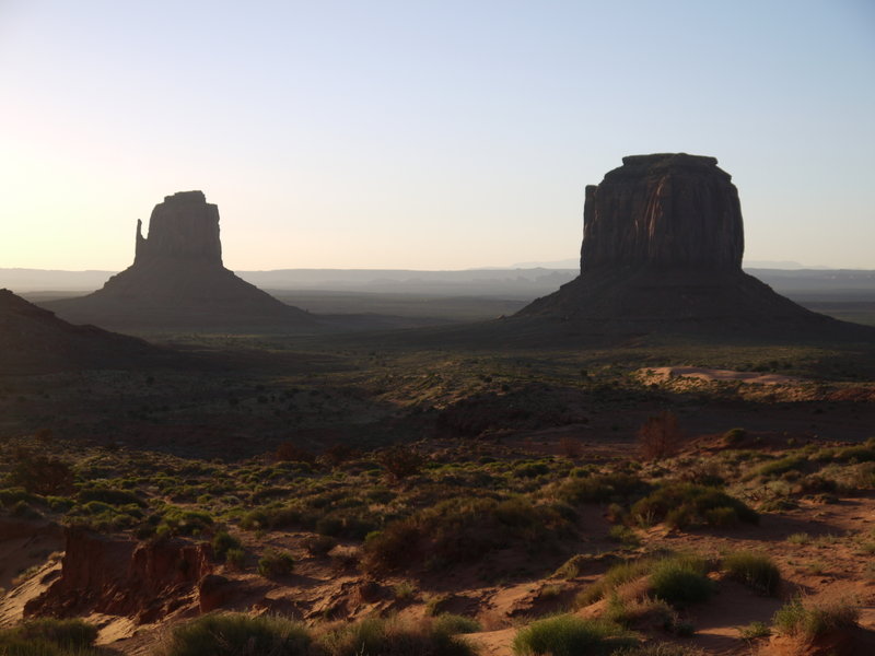 Two buttes at Monument Valley cast shadows over the land in the early morning light.