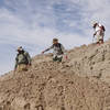 Three Monday Maniacs descend a mud hill.