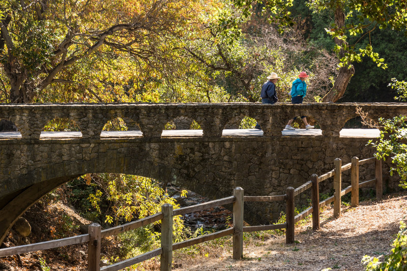 A couple crosses the stone bridge to reach the Penitencia Creek Trail.