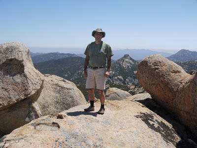 A hiker poses atop Gaskill Peak with Lawson Peak in the center-right.