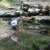 A visitor feels the cool water flowing out of Echo River Springs. Photo credit: NPS Photo.