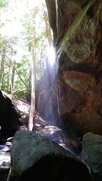 A waterfall trickles down the rocks past Hawk Creek Suspension Bridge.