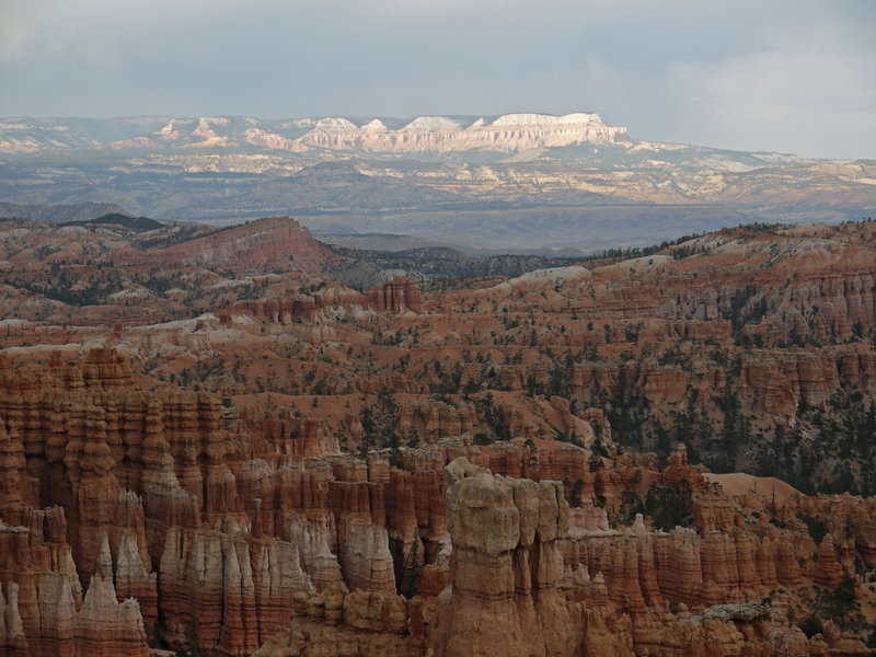 Dusk falls at Byrce Canyon as the last rays of sun illuminate The Backbone six miles away, a couple of mile northeast of the small town of Tropic