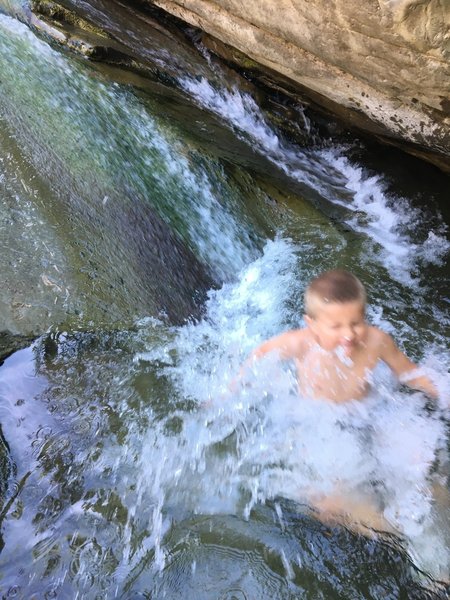 A child slides into a pool in the river next to Cross Camp.