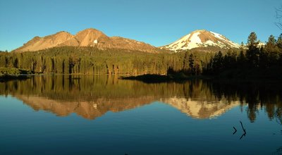 Manzanita Lake mirrors Chaos Crags on the left, and Mt. Lassen on the right, on a warm summer evening.