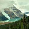 Mt. Robson in the clouds, with Berg Lake at its foot, and the mountains across the Robson River Valley in the distance, looking southwest from high on Mumm Basin Route