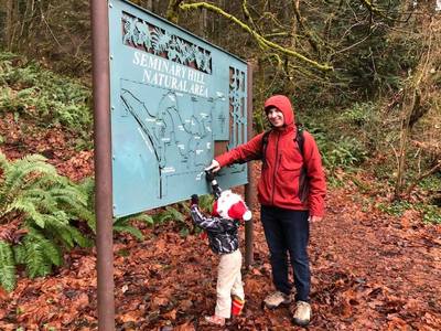 John and Cole are pointing to their current location on the beautiful trail map at the entry to the natural area.