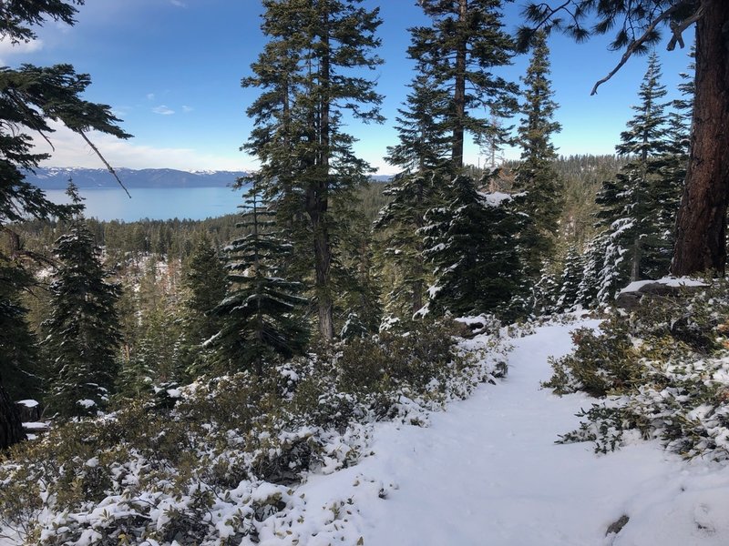 View of the lake with a few inches of snow on the trail