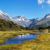 A green meadow with an alpine lake in front of Mount Christina