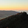 Some hikers enjoy sunrise on Piton des Neiges' sub-peak with Piton de la Fournaise in the far distance.