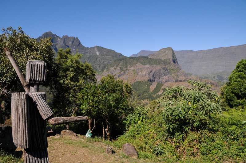 A wooden statue of a hiker can be found near a picnic table at the southern base of Piton Cabris. In the distance is Grand Benare.