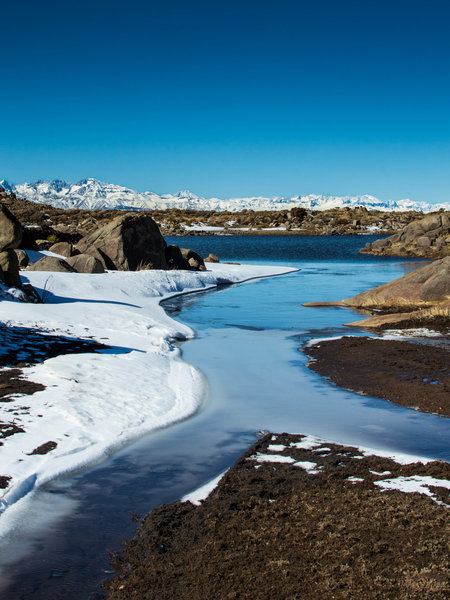 View of Laguna Del Inca after a snowfall, with the Andes mountain range hundreds of kilometers away rising in the background.