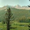 Turquoise Poboktan Creek flows through a lush meadow below Waterfall Peaks on a sunny August morning on the Poboktan Pass Trail.