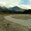 The Smoky River spread out across gravel flats, making for a lower water level and easier ford. Tatei Ridge is the mountain in the center with Chetang Ridge to its left. Seen looking upstream (southeast) at the alternate Smoky River crossing.