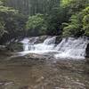 Smaller waterfall leading up to larger falls with swimming hole