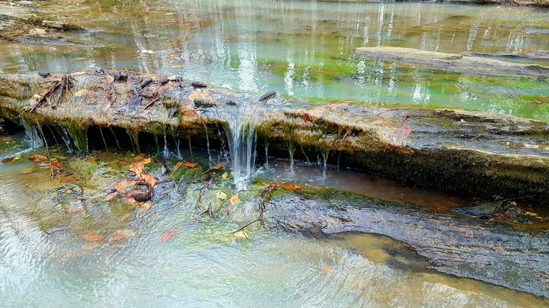 What mineral is causing the cloudy white appearance of the streams seen on this trail?